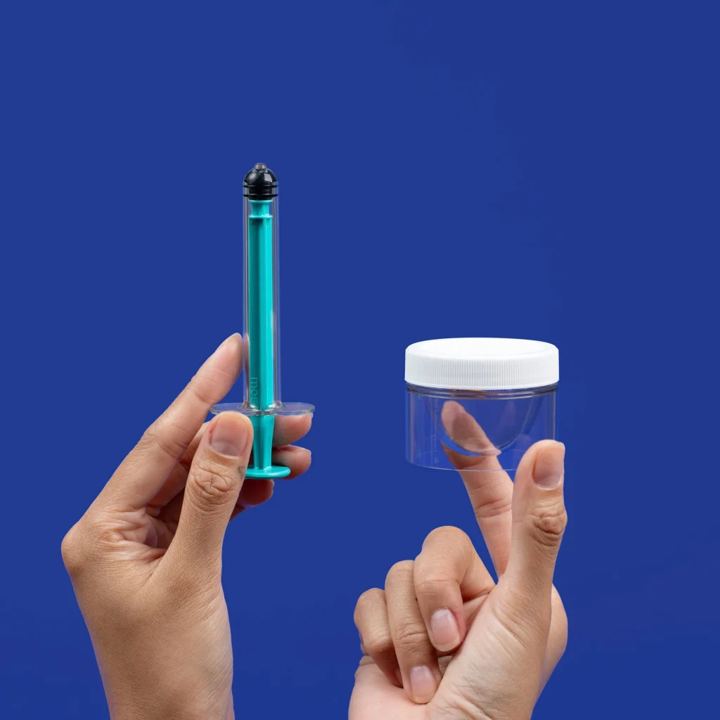 syringe and container for home insemination kit against a blue background