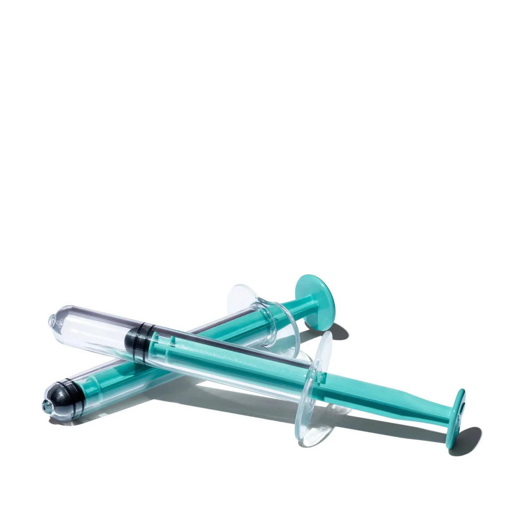 two teal syringes lying on a white background, designed for at-home insemination use